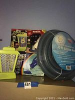 View of all items in the lot showing the yellow bug zapper, electronic insect trap boxes, and rolled up 35 ft pool vacuum hose.