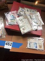 Clear ziplock bags with assorted postage stamps on top of a red envelope or album