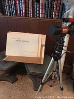 Tasco 9VR telescope and framed First World War posters with two dark wooden end tables beneath posters.