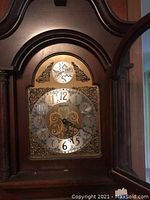 Close-up of clock face showing Tempus Fugit inscription, large Arabic numerals, and ornate design on dial.