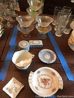 Photo showing the full lot of 3 Wedgwood pieces and surrounding glassware on table.