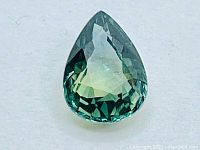 Close-up image showing the pear cut shape of the green sapphire with visible internal details and natural inclusions.