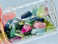 Close-up photo showing the mixed-color terminated Tourmaline crystals inside a small glass bottle with cork stopper.