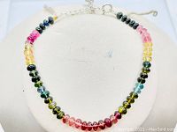 Full view of the round polished mixed color tourmaline beads arranged in sequence on the bracelet, showing the variety of colors from pink through green to yellow and blue.