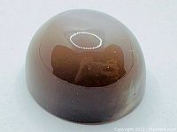 Oval cabochon cut deep smokey grey moonstone with reflective surface showing large cats eye effect.