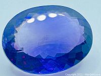 Close-up of large deep purple oval amethyst gemstone showing facets and polish.