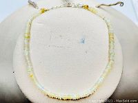 Full view of Ethiopian opal bracelet laid flat on a white padded display. Shows the color, size, and smooth round opal beads.