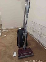 Full view of Kenmore canister vacuum with hose and wand upright, positioned on carpet.