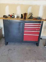 Front view of full workbench showing cabinet on left and five drawers on right under wood top