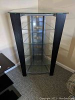 Front view of the entertainment stand showcasing glass shelves, dark wood side panels, and glass top.
