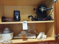 Photo showing Krups espresso machine with portafilter on wooden shelf, Hamilton Beach coffee grinder, and Krups juicer with accessories below.