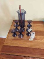 Photo showing all eight hand-blown martini glasses around a tall hand-blown pitcher and rectangular glass tray beneath.