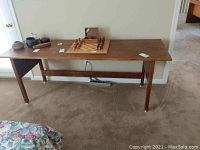 Full view of wooden table topped with some small items including a chess set, showing full length and design.