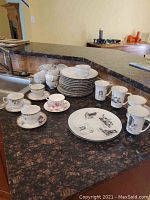 Photo showing multiple snack/luncheon plates stacked with cups and saucers around, including various patterns and sizes.