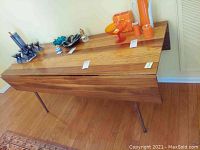Wide perspective view of the wooden drop leaf table showing the flat surface, decorative items on top excluded as not included in sale