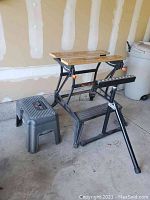 Black & Decker Workmate 300 folding workbench with adjustable wood roller stand and Rubbermaid step stool placed on garage floor.