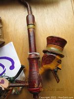 Close up of carved wooden soldier head pipe with hat, showing detailed carving and painted accents.