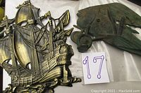 Photo showing detailed bronze ship wall art with sails and rigging, and partial view of cast iron airplane figure.