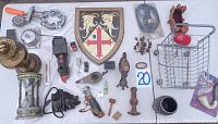 Photo of all items spread out on a white surface, showing mini shopping cart, crest shield, bicycle bell and other miscellaneous items.