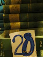 Photo showing six volumes of the Dickens Works hardcover book set with green covers and gold embossed titles on the spine. A blue and white card marked '28' is placed in front of the books for identification.