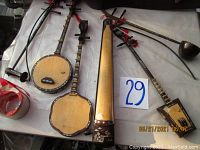 Full-size wooden stringed instruments laid out on a surface, showing round-bodied and rectangular-bodied varieties with long necks and decorative elements