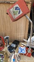 Photo showing assorted items including black Corvette model car, red railroad lantern replica, silver color cup, bronze nautical mirror, metal tea kettle, and steamship miniature.