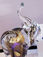 Front-angled view of clear glass elephant with trunk raised