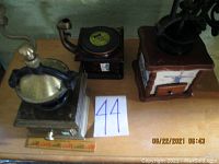 Three coffee grinders on a wooden table, showing overall condition and style of each grinder.