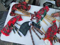 Multiple bagpipes on a white table, various tartan plaid bags visible.