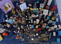 Top-down image showing a large assortment of vintage cologne and perfume bottles arranged neatly on a flat surface with some boxed items and varying bottle shapes and colors.