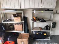 Two gray plastic shelving units side by side with various household items on and around them.