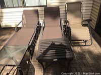 Image showing three patio chairs and two side tables arranged outdoors on brick patio.