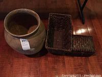 Clay pot and two woven baskets set on wood floor, one large open basket and one smaller basket with lid