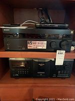 Front view showing Sony AV receiver on top and Mega Storage 300 CD player below in wooden shelf.