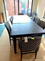 Photo of ten upholstered dining chairs arranged around two black tables pushed together, showing lacquered wooden frames and diamond pattern upholstery.