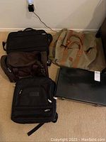 Overview of all bags and laptop on floor showing condition and brands visible