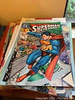 Stack of comics with visible cover showing Superman holding animals, titled 'Superman for the Animals'. Other comics are partially visible.