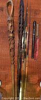 Full view of the two walking sticks, three spears and two cutters arrayed on a wooden floor