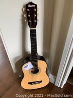 Full body view of Baron 33-inch acoustic guitar standing on the floor against a white wall.