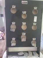 Front view of wooden bean bag toss game board showing scoring holes with point values and some bean bags inserted.