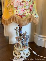 Full view of porcelain Capodimonte lamp with floral fabric shade showing putti angel figures and ornate base.