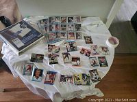 Wide view of various hockey cards spread out on white cloth, showing variety of players and card styles.