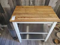 Front view of kitchen cart showing butcher block top and two stainless shelves
