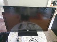 Front view of the LG 42 inch TV on a table showing the screen and the base stand.