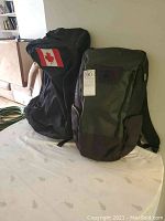 Two heavy-duty knapsacks: MEC convertible bag with Canadian flag and OGIO camping knapsack side by side.