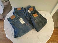 Four pairs of new Levi's jeans laid out on a white surface showing tags and back side including red Levi tab and branded leather patch.