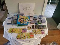 Overview of table with multiple groups of trading cards laid out and numerous plastic storage boxes for cards.