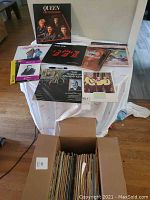 Photo showing multiple vinyl records including Queen Greatest Hits, Loggins & Messina, The Police albums, and a box of many more records below