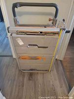 Front view of folded Rigid table saw on stand with handle, showing wear and condition.