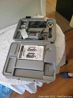 Full open view of plastic carrying case with Rotozip Spiral Saw handheld power tool inside with power cord, owners manual, and accessory compartments.